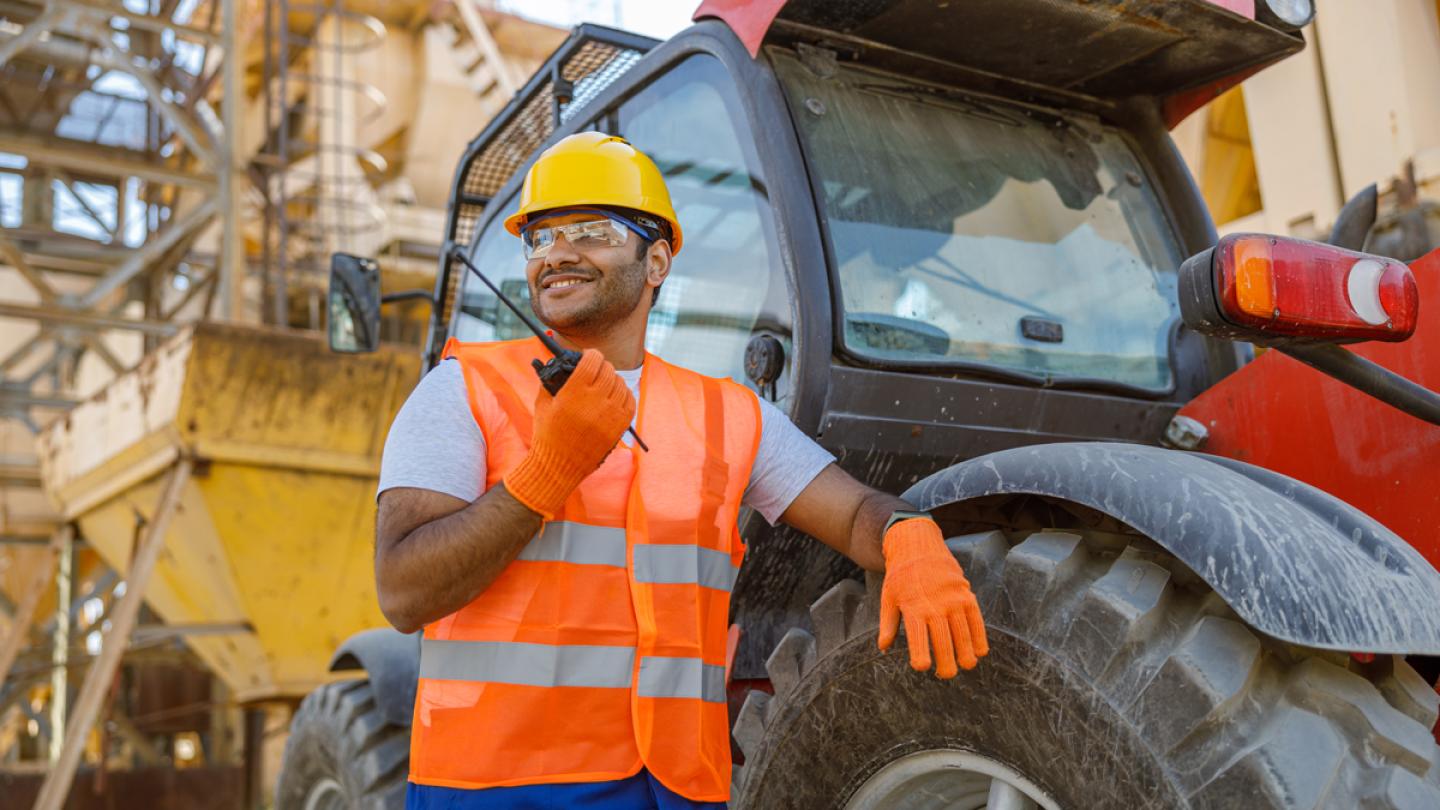 Man leaning on tire of construction vehicle