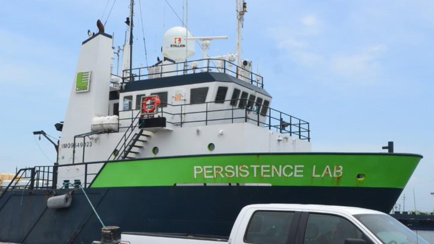 Truck parked on dock near cargo ship